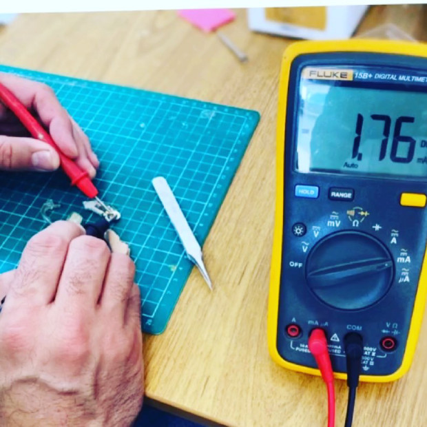 Técnico especialista reparando aparelho auditivo em bancada de laboratório